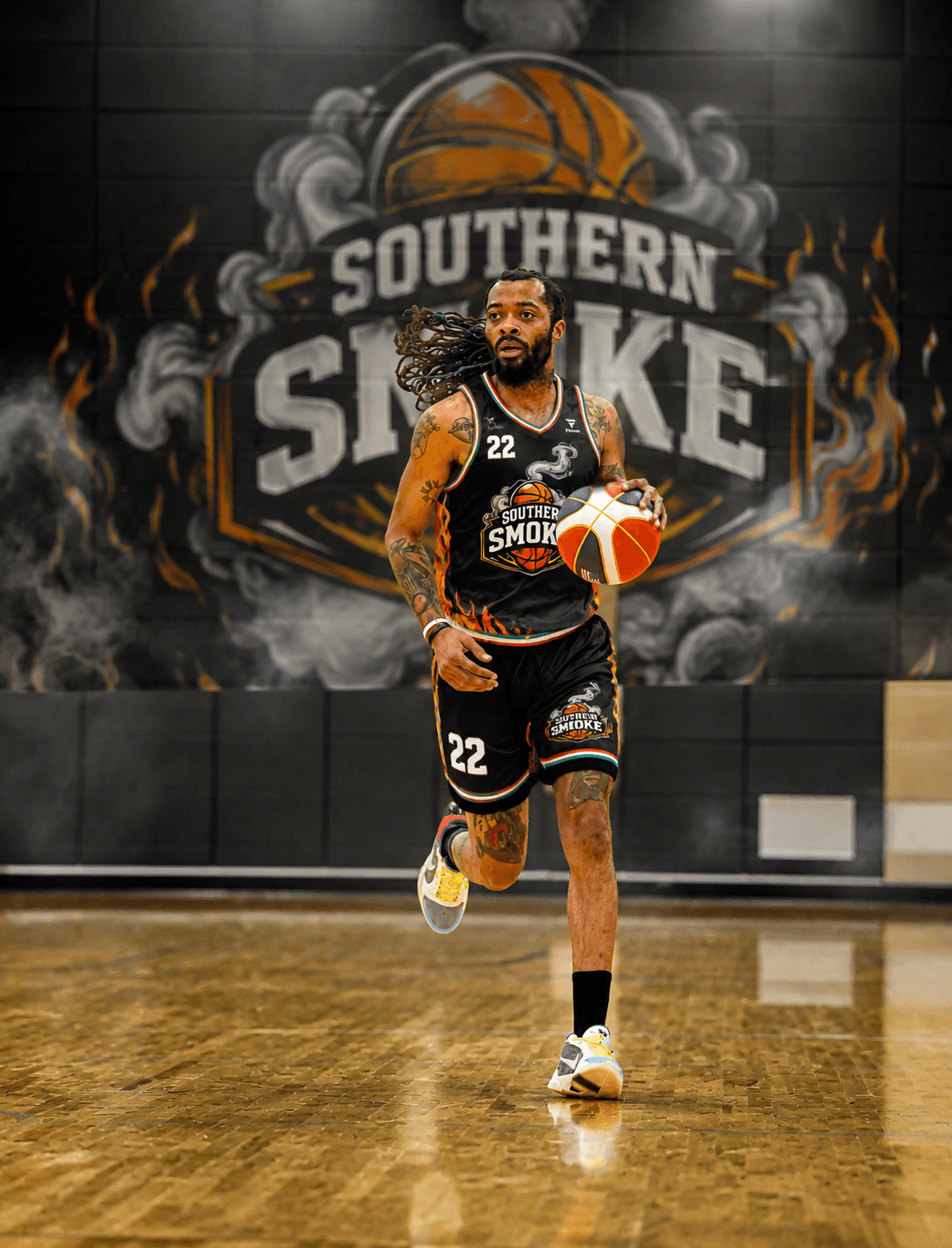 Tattooed basketball player with dreadlocks dribbles a ball in front of a Southern Smoke mural.