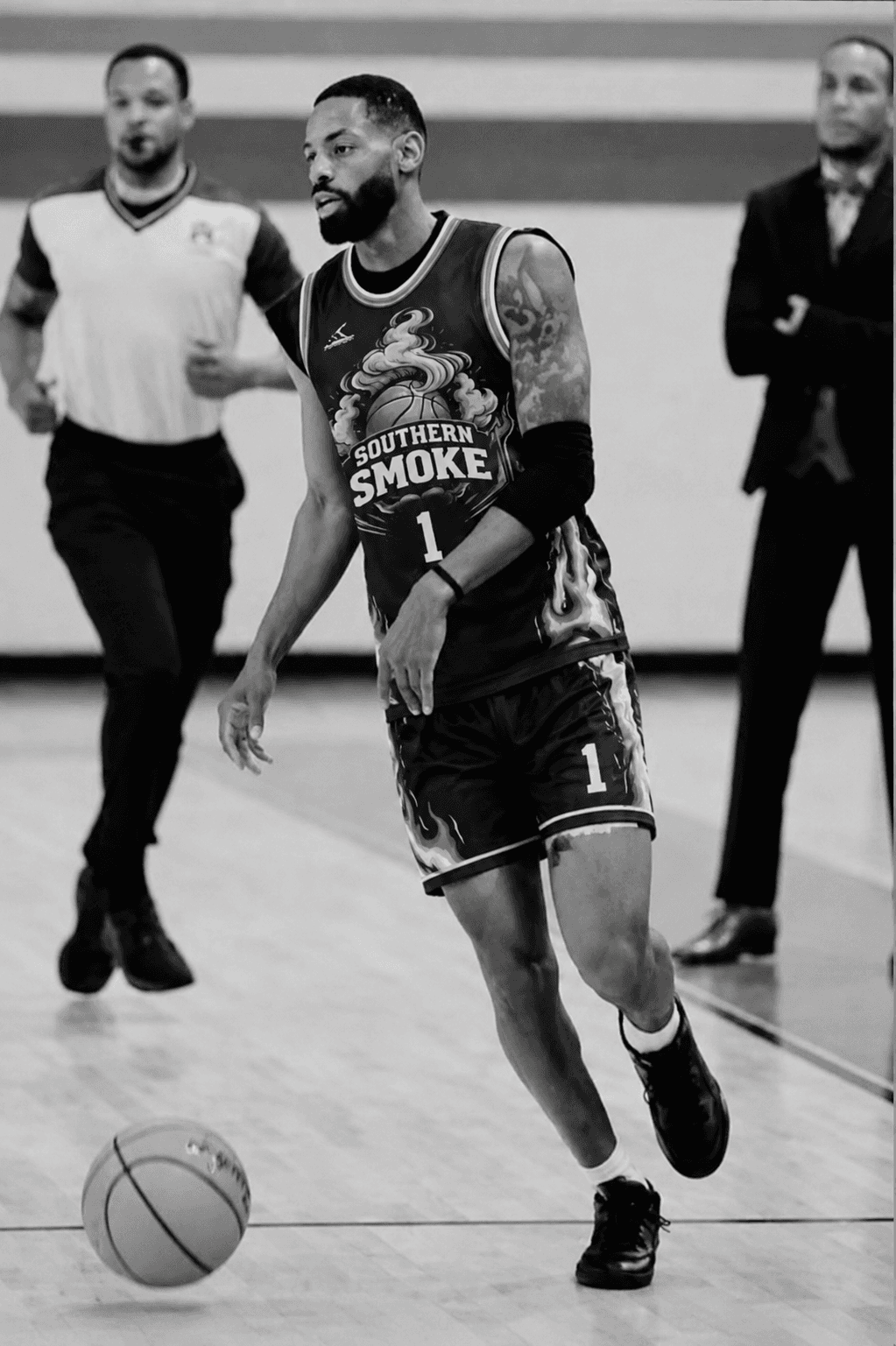 Bearded basketball player in a Southern Smoke jersey dribbles a ball on the court.