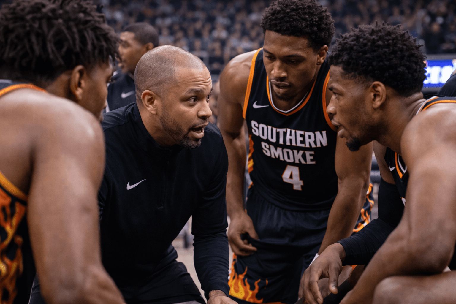 Coach speaks intensely to three Southern Smoke basketball players in a huddle.